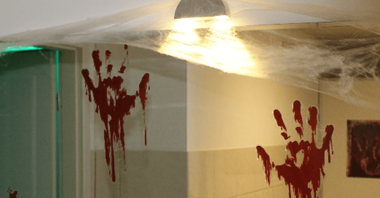 A Halloween-decorated room with a mirror covered in stickers of bloody handprints