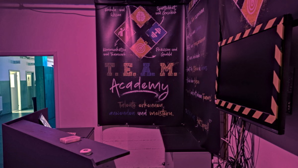 A reception area with a purple-lit wall featuring graphics and text promoting the T.E.A.M. Academy