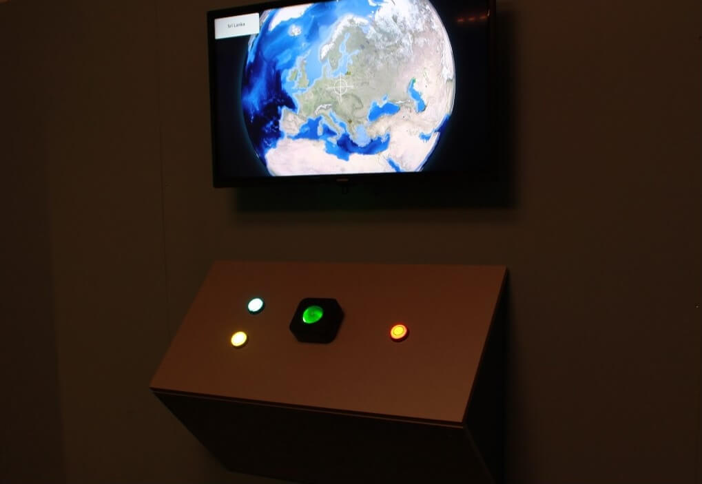 A screen with a globe, below which is a console with a glowing trackball and three buttons